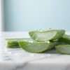 Fresh sliced aloe vera leaves with clear gel and water drops on a white marble counter